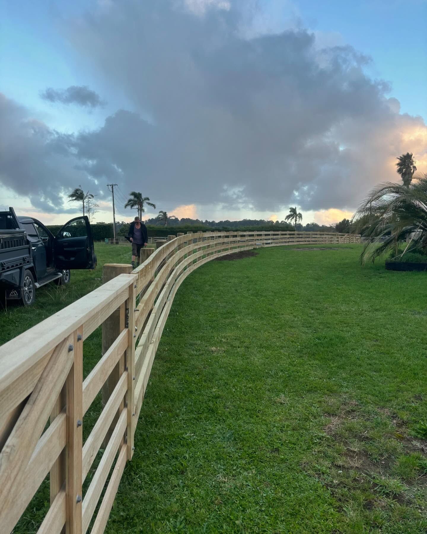 Curved post and rail fence under a dramatic Rodney sky